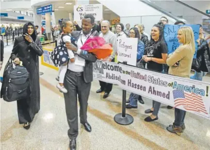  ?? Associated Press file ?? Somali refugee Abdisellam Hassen Ahmed, whose arrival was delayed by President Donald Trump’s January travel ban, walks with his wife, Nimo Hashi, and their 2-year-old daughter, Taslim, at Salt Lake City Internatio­nal Airport on Feb. 10.