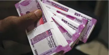  ?? Reuters ?? ↑ A cashier displays 2000 Indian rupee notes inside a bank in India.