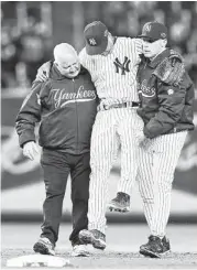  ?? Al Bello / Getty Images ?? Yankees shortstop Derek Jeter is carried off of the field by trainer Steve Donohue, left, and manager Joe Girardi after breaking his left ankle in the 12th inning of Saturday’s ALCS game at Yankee Stadium.