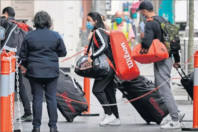  ??  ?? Varios jugadores retornan al hotel Grand Hyatt de Melbourne desde los torneos después de conocerse que debían aislarse para pasar otro test de coronaviru­s.