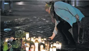  ?? VESA MOILANEN/LEHTIKUVA VIA AP ?? A woman places a memorial candle Friday evening at the Market Square for the victims of stabbings in Turku, Finland.