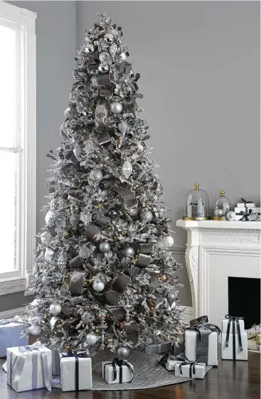  ?? Thomas Kuoh courtesy Balsam Hill ?? A flocked Balsalm Hill tree sparkles when adorned with ornaments in shades of pewter and silver.