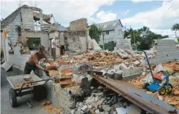  ?? CHUZAVKOV/GETTY-AFP SERGEI ?? Men work on rebuilding a destroyed home Wednesday in Makariv, Ukraine, west of Kyiv.