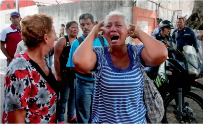  ?? AFP ?? A relative of a prisoner cries in front of a police station in Valencia, after a fire engulfed police holding cells. —