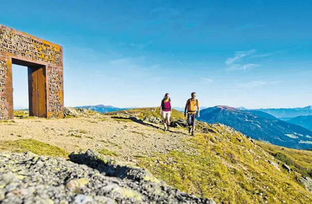  ?? FOTOS: FRANZ GERDL/LUDGER OSTERKAMP (2) ?? Wahrzeiche­n: Wanderer passieren das Granattor auf 2.060 Metern Höhe. Es erzählt die Geschichte des rubinroten Edelsteins Granat, der nirgendwo in den Alpen so oft vorkommt wie hier.