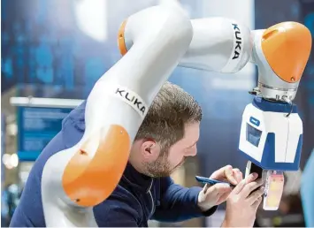 ?? Foto: Friso Gentsch, dpa ?? Mensch und Roboter arbeiten Hand in Hand. Das ermögliche­n Kuka Roboter und der blaue Greifer von Schunk auf unserem Bild. Bald könnten die Roboter aber auch selbst aus ihren Fehlern lernen. Software macht es möglich.