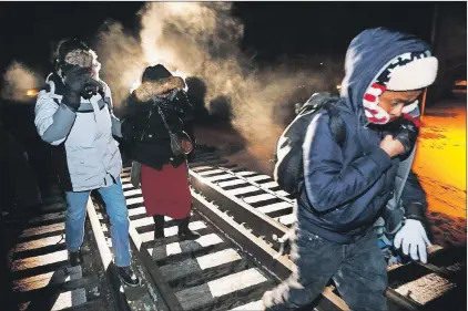  ?? CP PHOTO ?? Early Sunday morning, eight migrants from Somalia cross into Canada illegally from the United States by walking down this train track into the town of Emerson, Man., where they will seek asylum at Canada Border Services Agency.