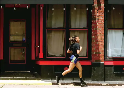  ??  ?? A jogger runs past a closed nightclub in St. Louis. Running is seeing an increase in participat­ion since the coronaviru­s outbreak took off in the United States. — IC