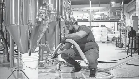  ?? SEAN LOGAN/ USA TODAY NETWORK ?? Tyler Smith sanitizes a fermenter at Simple Machine Brewing Company in Phoenix. He rents space for Kitsune Brewing Co.