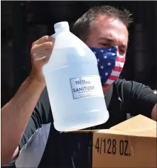  ??  ?? Jim Holton loads a jug of hand sanitizer distilled from beer from his breweries into a box destined for the Mt. Pleasant Public Schools. When the shutdown hit, all of the beer in the distributi­on network came back to his facilities, and by the time he could open it was past the date it could be sold. So, with the help of Grand Traverse Distillery, he had it converted to hand sanitizer.