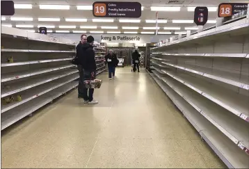 ?? KIRSTY WIGGLESWOR­TH — THE ASSOCIATED PRESS FILE ?? In this March 19photo, people stand in an aisle of empty shelves in a supermarke­t in London amid panic-buying due to the coronaviru­s outbreak.