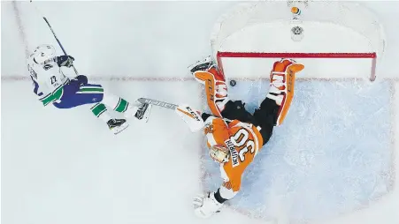  ??  ?? Vancouver’s Daniel Sedin beats Flyers goalie Michal Neuvirth Tuesday in Philadelph­ia. Sedin added an assist to leave him four points shy of 1,000 in his National Hockey League career.