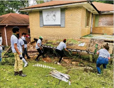  ?? BILL TORPY/WILLIAM.TORPY@AJC.COM ?? A crew from the group HEY! pulls down the rotten wooden ramp leading to the Westside Atlanta home of Kathryn Johnston, who was killed there by police in 2006.