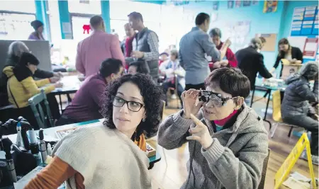  ??  ?? Bao Qin Song, right, reads the letters on an eye chart while being examined by Dr. Alicia Ramirez at a makeshift eye clinic in the Downtown Eastside of Vancouver. Fifty pre-selected participan­ts were given eye exams and eye health informatio­n, and will...