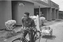  ??  ?? A deliveryma­n sets off with stoves and pellets for an Inyenyeri customer in Gysenyi, Rwanda. Inyenyeri is betting that it can give away stoves and make money by charging for fuel.