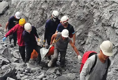  ?? ?? Firefighte­rs and workers evacuate a body from a quarry in Hualien County, eastern Taiwan, in a photograph released by the Hualien Fire Department