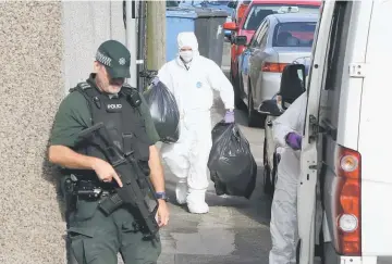  ??  ?? Police forensic officers carry evidence from a residentia­l address in Larne, Co Antrim, Northern Ireland in one the searches at addresses carried out by police and the army bomb squad in connection with the arrest of a British soldier in southwest...