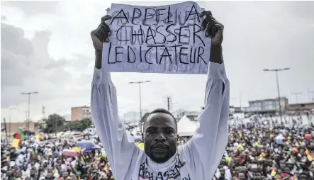  ?? MARCO LONGARI/AFP/GETTY IMAGES ?? A man holds a sign saying “A call to dismiss the dictator” in French in front of a crowd of supporters of the leader of the Cameroonia­n opposition party prior to the Oct. 7 national vote.