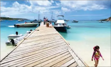  ?? NECEE REGIS/THE WASHINGTON POST ?? A child wades through the water along the pier at Road Bay in Sandy Ground on the Caribbean island of Anguilla.