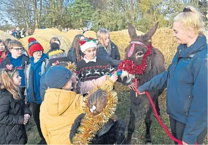  ?? ?? FESTIVE: Pupils from Macduff Primary School meet Dora the donkey at Netherwood and librarian Marjory Nicholson is given a special farewell by head teacher Helen James