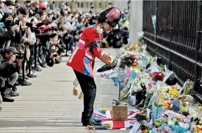  ??  ?? An ardent Royals fan lays a floral tribute at the front of Buckingham Palace in central London Friday after the announceme­nt of the death of Britain’s Prince Philip, Duke of Edinburgh, aged 99. — AFP