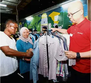  ??  ?? Doing the needful: Chan (right) and Dr Rusaslina helping former driver Jalaludin choose clothes at Kedai Jalanan.