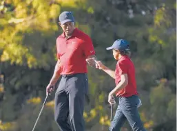  ?? SCOTT AUDETTE/AP ?? Tiger Woods fist-bumps his 12-year-old son Charlie during the PNC Championsh­ip on Sunday. Woods played his first competitiv­e golf since February’s horrific car crash.