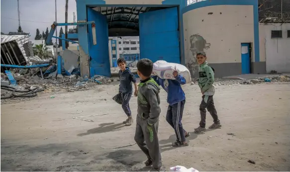  ?? AFP ?? Children carry flour after humanitari­an aid was distribute­d in Gaza city yesterday. A convoy of seven lorries delivered supplies to the city in the north of the strip