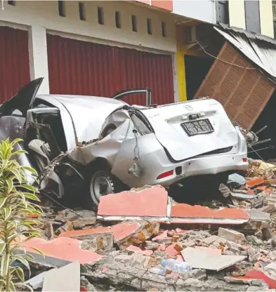  ?? ANTARA FOTO / AKBAR TADO VIA REUTERS ?? A crushed car sits in rubble after a 6.2-magnitude earthquake killed dozens of people on the Indonesian island
of Sulawesi on Friday. The temblor also damaged more than 300 homes, two hotels and flattened a hospital.