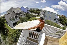  ?? AP ?? Tim Avery pulls boards to the third story of a home as he prepares for Hurricane Florence at a home in Emerald Isle N.C., on Wednesday.