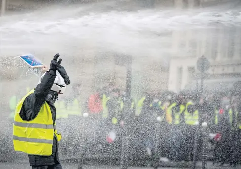  ?? EPA ?? A yellow vest protester holds his hands up as riot police water cannons spray water near Avenue Marceau, during the demonstrat­ion in Paris, France on Saturday.