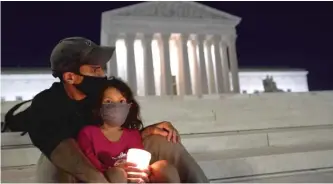  ?? ALEX EDELMAN/AFP VIA GETTY IMAGES ?? A girl holds a candle in front of the Supreme Court building in Washington, D.C., paying respect to Justice Ruth Bader Ginsburg, who died Friday at age 87.