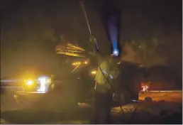  ?? ETHAN SWOPE — THE ASSOCIATED PRESS FILE ?? A Pacific Gas and Electric employee sprays water on a burning telephone pole at the Zogg Fire near Ono.