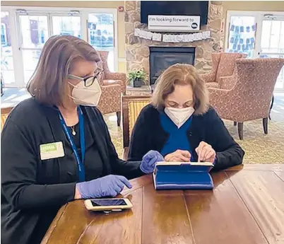  ?? ATRIA ?? A masked and gloved Barbara Moran, director of social programs for Atria Senior Living, helps resident Paula Mont, 86, shop online in Cranford, New Jersey. The coronaviru­s pandemic has sparked a surge of online shopping across all age groups, including from older adults.