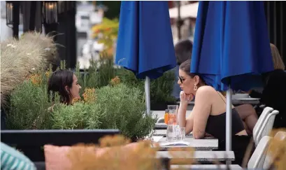  ?? DARRYL DYCK THE CANADIAN PRESS ?? Two women have drinks on the patio at an Earls restaurant in Vancouver on Tuesday. Dr. Theresa Tam, Canada’s chief public health officer, said “there is no one size fits all” strategy to reopening provinces and territorie­s.