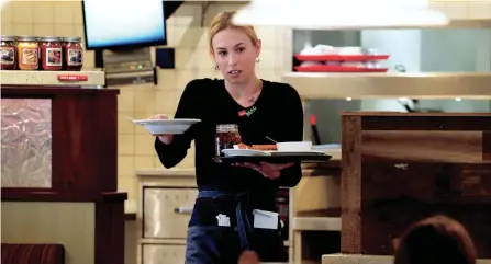  ?? ?? Mackenzie Mccory carries food and drinks for a customers at Bob Evans restaurant in Blue Ash, Ohio.