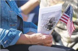  ?? RICK KINTZEL/THE MORNING CALL ?? A woman holds two American flags and a program Saturday during a remembranc­e service at Good Will Fire Company No. 1 of Trexlertow­n in Upper Macungie Township.