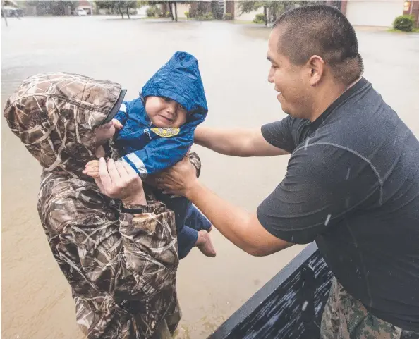  ?? Picture: AP ?? FLOOD DRAMA: Wilfredo Linares reaches out for his baby, Mason, as they are evacuated from Grand Mission subdivisio­n in Fort Bend county, Texas. The rising floodwater­s from Tropical Storm Harvey have forced the evacuation of thousands of people.