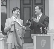  ?? PAUL FAITH/AFP/GETTY IMAGES ?? Prime Minister Justin Trudeau is given a rugby jersey and pair of socks Tuesday in Dublin by Ireland’s Prime Minister Leo Varadkar.