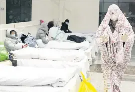  ??  ?? OUTBREAK A patient in a blanket arrives at a hospital built two days ago in Wuhan