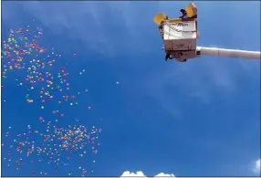  ?? Westside Eagle Observer/SUSAN HOLLAND ?? Colorful plastic balls are tossed out from the bucket of an Empire Electric Company truck and descend from the clear blue sky in the popular money drop sponsored by the Bank of Gravett. Those who scrambled fast enough to collect balls with numbers were able to exchange them for cash prizes at the bank.