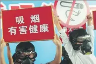  ?? LIAN GUOQING / FOR CHINA DAILY ?? Children wearing gas masks hold anti-smoking signs to call on their parents to quit smoking at an event in Hangzhou on May 29, 2016.