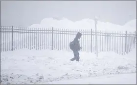  ?? (AP/Joshua Bessex) ?? A person walks through downtown in the snow Friday in Buffalo, N.Y.