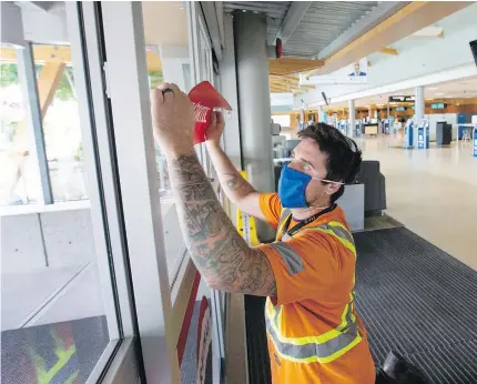  ??  ?? Neris Masiulis installs exit signs in the departure area at Victoria Internatio­nal Airport.