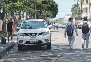  ?? FOTOS: RICHARD CASTRO / EXPRESO ?? Los estudiante­s de la U. E. Ileana Espinel, deben caminar por la calzada porque la acera está ocupada.