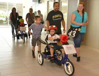  ?? Robin Rombach/Post-Gazette ?? Ethan Klein, 4, gets some help from his brother Jacob Klein, 7, and his parents, Lindsay Klein and Arturo Hernandez, as they ride in the bike parade through the halls of the Allegheny Health Network Wexford Health + Wellness Pavilion.