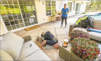  ??  ?? HOMEOWNER Galit Naor of Oak Park looks on as Slyapich searches her property for rattlesnak­es in July. At the time, Naor said she had spotted three snakes on her land in the previous two weeks.