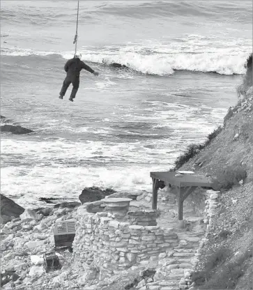  ?? Mark Boster Los Angeles Times ?? A WORKER is hoisted by a helicopter while securing heavy equipment to dismantle one of the two stone porches on the shoreline of Lunada Bay in Palos Verdes Estates. The surf spot is notorious for its localism.