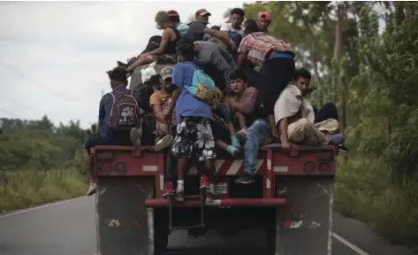 ?? AP PHOTO/MOISES CASTILLO ?? Migrants ride on the back of a freight truck that slowed down to give them an opportunit­y to jump on in Rio Dulce, Guatemala, on Friday.