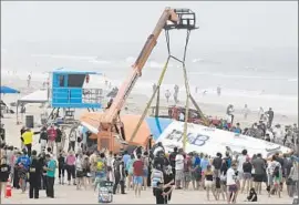  ??  ?? A CRANE lif ts the surf board, which measures 421⁄4 feet long, 11 feet 1 inch wide and 16 inches thick. The record for biggest surf board hasn’t been confirmed.